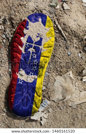 The flag of Venezuela is depicted on the sole of an old boot. Ecology concept with environmental pollution from household and industrial waste.