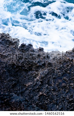 A close up of black rock coastline and deep blue sea
