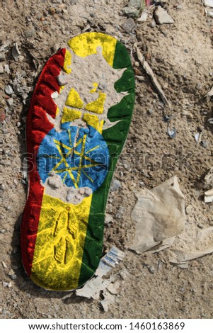 The flag of Ethiopia is depicted on the sole of an old boot. Ecology concept with environmental pollution from household and industrial waste.