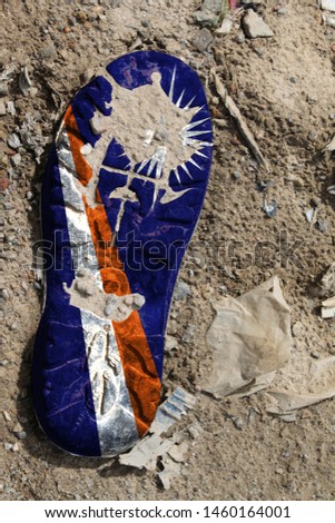 The flag of Marshall Islands is depicted on the sole of an old boot. Ecology concept with environmental pollution from household and industrial waste.