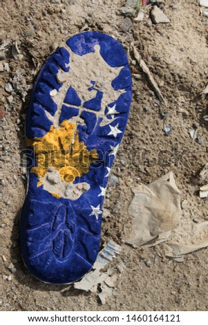 The flag of Kosovo is depicted on the sole of an old boot. Ecology concept with environmental pollution from household and industrial waste.