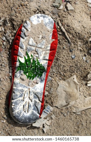 The flag of Lebanon is depicted on the sole of an old boot. Ecology concept with environmental pollution from household and industrial waste.