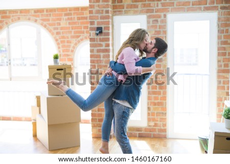 Young beautiful couple in love celebrating moving to a new home around cardboard boxes