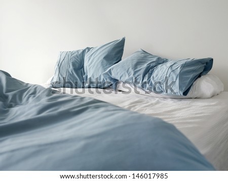 Morning view of an unmade bed with crumpled blue bed linens and no people Royalty-Free Stock Photo #146017985