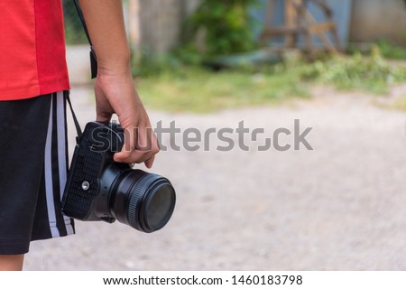 kid boy holding digital camera or DSLR on outdoor or park with copy space,mid section.