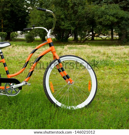 An orange bicycle standing on green meadow
