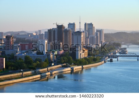 Sunrise in Pyongyang, North Korea and Taedong River in the morning fog. View facing upstream, modern residential complex and new construction site. View from Yanggakdo island Royalty-Free Stock Photo #1460223320