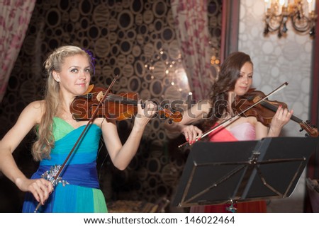 violin duet of girls playing in the restaurant
