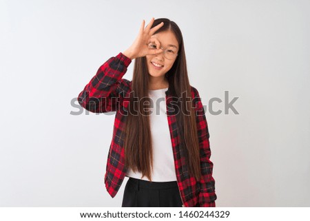 Young chinese woman wearing casual jacket and glasses over isolated white background doing ok gesture with hand smiling, eye looking through fingers with happy face.