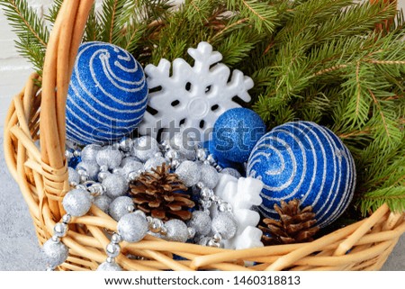 Christmas composition - wicker basket with decorations and fir branches on a light background close up