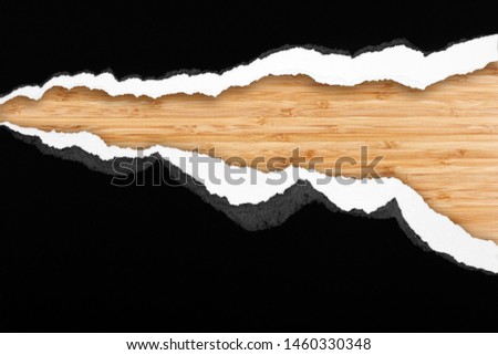 Ripped paper on wood background, space for copy