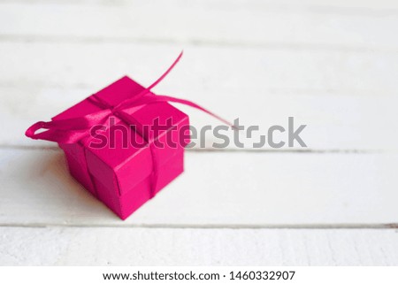 Red gift box with ribbon on white wooden background. copy space