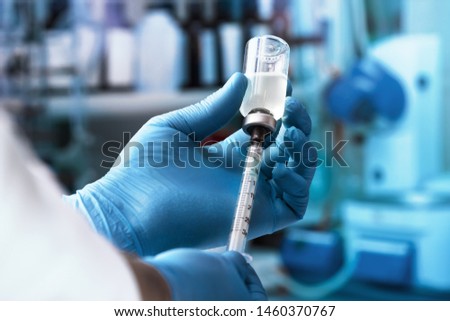 physician filling syringe with dose of vaccine / Doctor hand holding syringe and vaccine Royalty-Free Stock Photo #1460370767