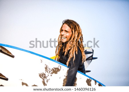 Lifestyle photography. A day in summer of a surf coach in a sunny beach.
 Young man with dreadlocks outdoors. 