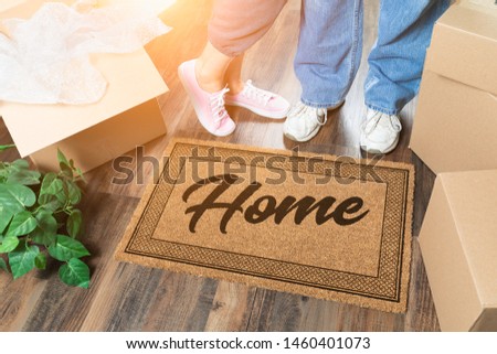 Man and Woman Unpacking Near Home Welcome Mat, Moving Boxes and Plant.