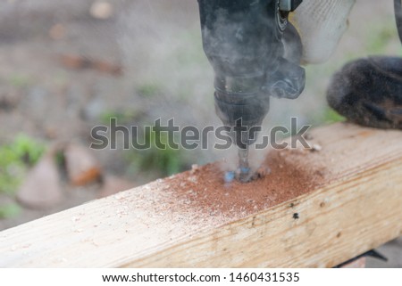 drill a hole in the board. Drill a hole in the timber. drill for wood.
