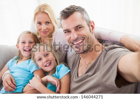 Man taking picture of wife and twins sitting on a couch in the living room
