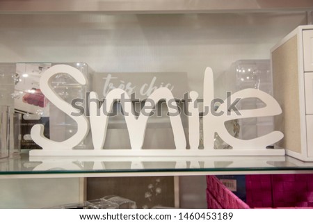 Decorative sign with the words "Smile" for sale inside of a home décor store.