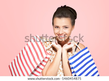 Image of a beautiful happy young blonde woman posing isolated over pink wall background holding shopping bags.