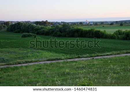 Only open green, yellow field forest and clouds on blue sky in summer, sunny day. Good weather. Away, far hills, trees. Mysterious, magical, fantastic panoramic landscape place. Photography background