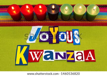 JOYOUS KWANZAA text word collage typography, seven candles and multi colored fabric on green woven fabric, African American holiday, horizontal aspect