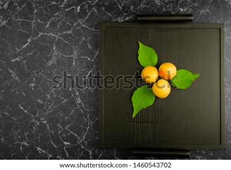 RIPE APRICOTS LYING ON THE BLACK TRAY ON DARK BACKGROUND