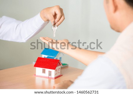 Real estate Sales manager giving keys to customer after signing rental lease contract of sale purchase agreement, concerning mortgage loan offer for and house insurance.