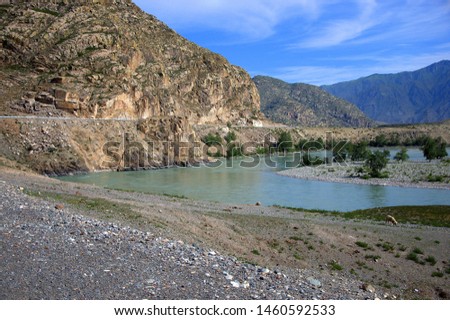 The rocky shore of the turquoise Katun River flowing at the foot of the mountains. Altai, Siberia, Russia.