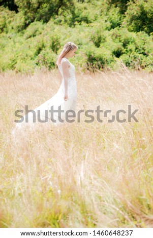 Beautiful young woman in a white vintage lace dress with pink hair walks across the meadow