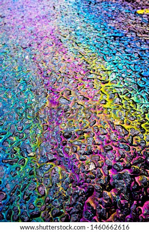 A leaked Car Oil Petrol in The Rain on a Tarmac Road Metallic Rainbow