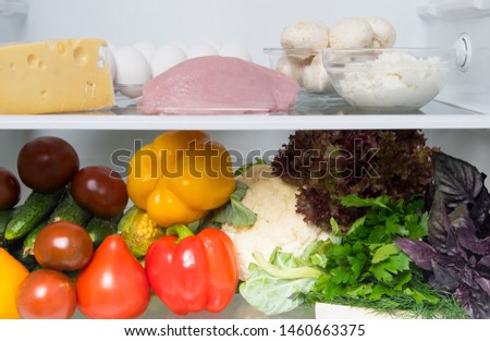 close-up, in the White Refrigerator food stock, on the top shelf are eggs, fish, mushrooms, cottage cheese, turkey meat, cheese, and fresh vegetables on the bottom