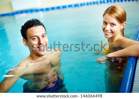 Image of young male and female looking at camera in water