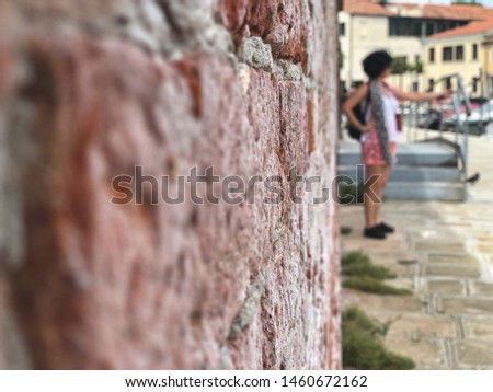 a woman taking selfie in front of a brick wall at street