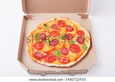 Image of fresh tasty pizza in cardboard box on white surface, picture of fast food dish, supper from restaurant or cafe. Fast food eating concept. Open box with delicious pepperoni pizza on table.