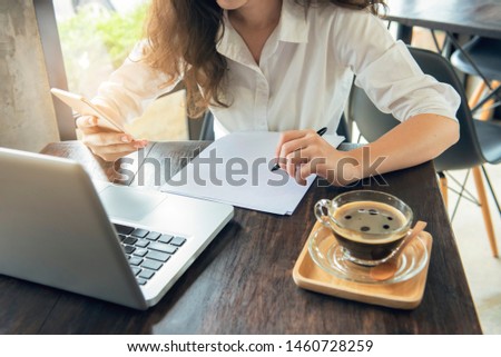 Hand of asian woman use smart mobile phone look at mobile and prepare paper for note.E-commerce, university education, internet technology, or startup small business concept.