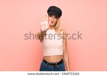 Young blonde woman with hat making stop gesture