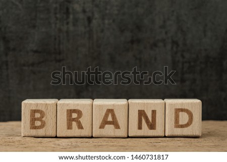 Brand communication for product and service advertising, wooden cube block with alphabet building the word Brand on wood table, dark black background.