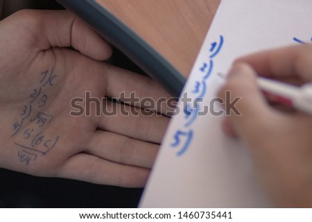 Student is cheating at exam with at school with answer written on his hand.