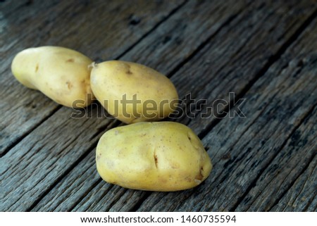 Fresh potatoes heap on an old wooden table, on rustic wooden background. Fresh organic food. Organic food, carbs, tubers.