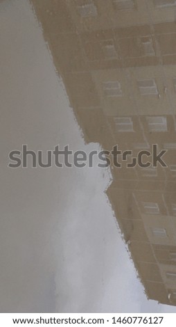 reflection of a multistory apartment building in a muddy and brown puddle