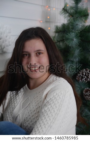 Portrait of a girl sitting on a ottoman by the Christmas tree