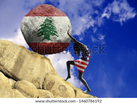 The girl, wrapped in the flag of united states, raises a stone to the top in the form of a silhouette of the flag of Lebanon