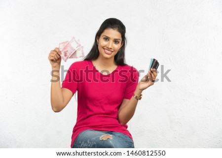 beautiful Indian woman holding money and cards isolated in white background