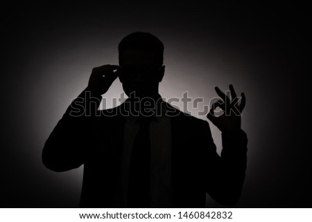 black silhouette of businessman showing ok sign with back light
