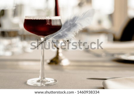 Red cocktail decorated with a feather at a restaurant
