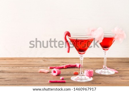 Glasses with tasty cotton candy cocktail and sweets on wooden table
