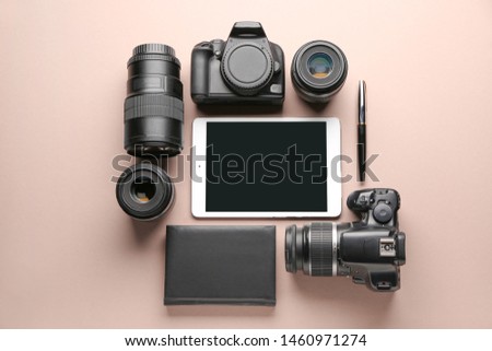 Tablet computer and set of photographer's equipment on color background