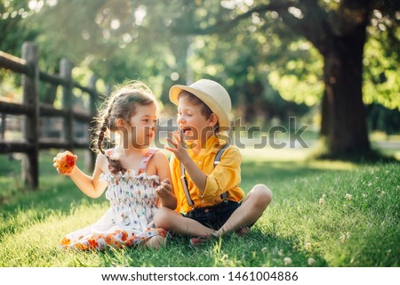 Caucasian children boy and girl siblings sitting together sharing apple. Two kids brother and sister eating sweet fruit in park on summer day. Best friends forever. Healthy happy childhood. Royalty-Free Stock Photo #1461004886
