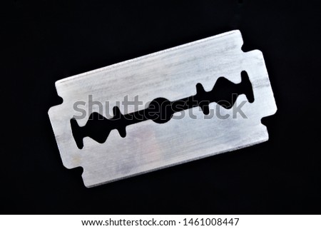 Razor blade on black background. The razor blade is a flat metal plate, it is a shaving tool. The blades for hair removal, have two sharpened cutting edges, installed in the shaving machine. Royalty-Free Stock Photo #1461008447
