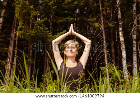 Woman practicing yoga in the fresh air. Meditation on the background of the forest. The concept of a healthy lifestyle. Yoga for beginners. Place for text.